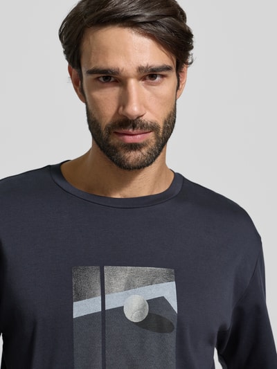 Männermodel trägt Relaxed Fit T-Shirt aus reiner Baumwolle Modell 'JOIN' von BOSS Green in Dunkelgrau mit Motiv-Print, Nahaufnahme Oberkörper.