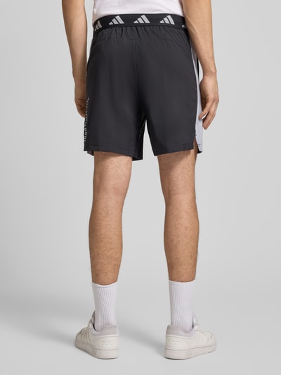 Mannenmodel draagt Shorts met Logo en elastische band van adidas Training, regular fit, zwarte kleur, bandwijdte M 38 cm, achteraanzicht, ganzekörper.