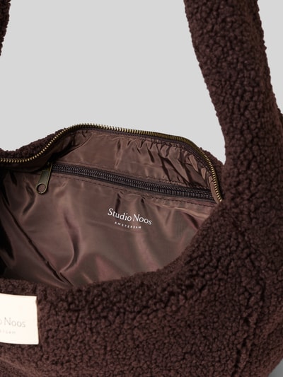 Produktfoto, Shoulder Bag aus Teddyfell von Studio Noos, futerko w odcieniu brązu, główna przegroda z zamkiem błyskawicznym, szeroki pasek na ramię, naszywka z logo, przegródka wewnętrzna zapinana na zamek błyskawiczny, szerokość w rozmiarze 1: 48 cm, długość w rozmiarze 1: 24 cm, głębokość w rozmiarze 1: 10 cm, długość paska: 90 cm, miękka faktura