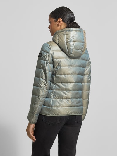 Männermodel trägt Jacke mit Kapuze von NAUTGÅRD, luźny krój, kaptur, tunel, ukryty zamek, detal z logo, pasek na rękawie, długość pleców w rozmiarze M: 90 cm, szerokość ramion w rozmiarze M: 45 cm, szerokość klatki piersiowej w rozmiarze M: 56 cm, długość rękawa w rozmiarze M: 60 cm, zielono-srebrna, pikowana tkanina, matowa tekstura, Ganzkörperansicht Rückansicht.