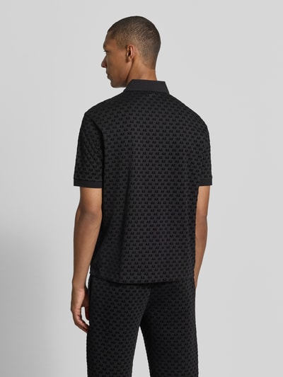 Männermodel trägt Regular Fit Poloshirt aus reiner Baumwolle von Armani Exchange mit Allover-Logo-Print in Schwarz, Ganzkörperansicht Rückansicht.