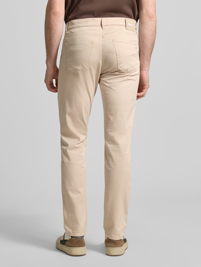 Męski model nosi spodnie z wpuszczanymi kieszeniami Model 'Chuck' od Brax, mieszanka bawełny i lyocellu, krój slim fit, długość wewnętrzna nogawki 81 cm, szerokość w rozmiarze 32/32: 43 cm, widok całej sylwetki z tyłu.
