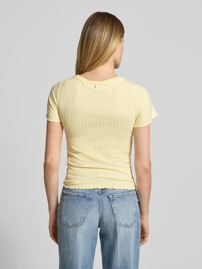 Frauenmodel trägt T-Shirt aus Viskose-Mix mit Rundhalsausschnitt von Rich & Royal, Strukturmuster, Straight Fit, Stretch-Anteil, Rückenlänge 51 cm bei Größe S, sanftes Gelb, feine Rippenstruktur, Ganzkörperansicht Rückansicht.