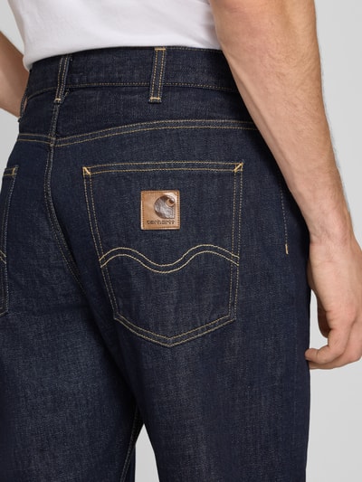 Männermodel trägt Slim Fit Jeans aus reiner Baumwolle Modell 'MARLOW' von Carhartt Work In Progress, dunkle Farbe, Detailaufnahme. Herren Jeans, 5-Pocket-Design, Knopf- und Reißverschluss, Bundweite 46 cm, Innenbeinlänge 83 cm.