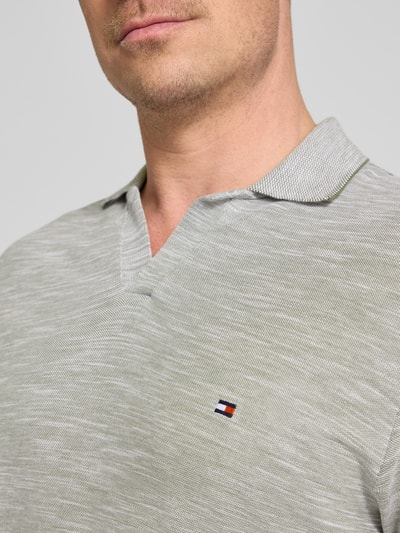 Männermodel trägt Regular Fit Poloshirt aus reiner Baumwolle von Tommy Hilfiger in Melange-Optik mit Logo-Stitching, Nahaufnahme Oberkörper.