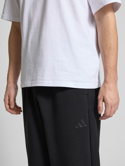 Männermodel trägt Comfort Fit Sweatpants mit Logo-Print von adidas Sportswear, Optik: Unifarben, Materialverarbeitung: Sweat, Nahaufnahme Oberkörper.