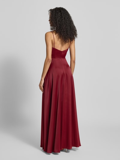 Frauenmodel trägt Abendkleid mit Wasserfall-Ausschnitt von Jake*s Cocktail in Bordeauxrot, aus Material-Mix mit Stretch, taillierter Schnitt, Spaghettiträger, blickdicht, Ganzkörperansicht Rückansicht.