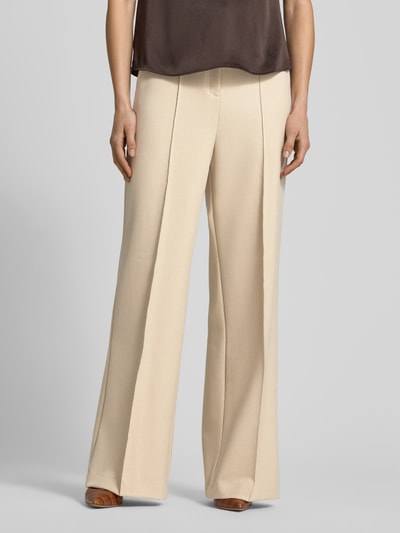 Frauenmodel trägt Wide Fit Stoffhose mit Viskose-Anteil Modell 'Paris' von Mango in Beige, Bügelfalten, elastisch, Nahaufnahme Unterkörper.
