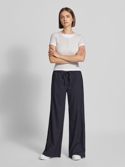 Vrouwenmodel draagt Wide Fit Hose met elastischem Bund van GUESS, donkerblauw met witte strepen, Bandplooien, Tunnelkoord, Ganzkörperansicht van voren. Bandwijdte maat 27/32: 41 cm, Binnenbeenlengte 80 cm.