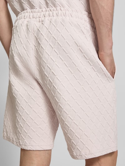 Mężczyzna nosi Relaxed Fit Sweatshorts mit Strukturmuster model 'Jovren' od Pegador, elastyczna mieszanka materiałów z mieszanką bawełny, wzór fakturowany, szerokość w rozmiarze M: 39 cm, długość wewnętrzna nogawki: 24 cm, zbliżenie na tył