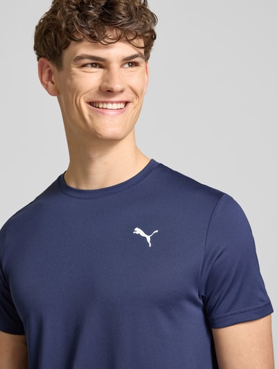 Männermodel trägt Regular Fit T-Shirt mit Logo-Print Modell 'Solid' von PUMA PERFORMANCE in Dunkelblau, Nahaufnahme Oberkörper.