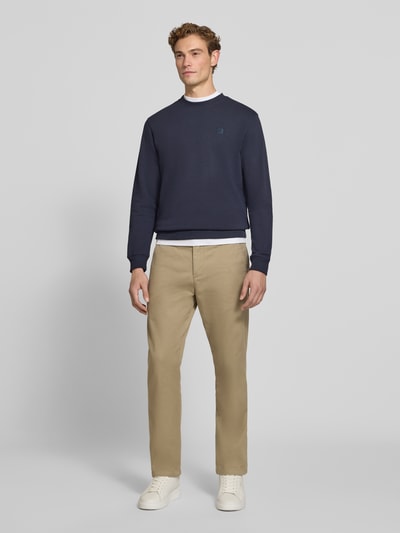 Männermodel trägt Regular Fit Sweatshirt aus reiner Baumwolle mit Label-Patch von Scotch & Soda in Dunkelblau, Ganzkörperansicht von vorne, Herren Sweatshirt mit elastischen Abschlüssen, Rückenlänge 70 cm, Ärmellänge 66 cm.