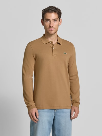 Männermodel trägt Regular Fit Poloshirt aus reiner Baumwolle von Lacoste in Braun mit glatter Textur, Ganzkörperansicht von vorne. Herren Poloshirt von Lacoste.