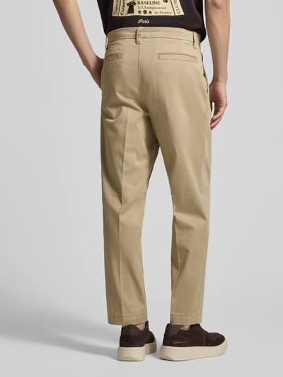 Männermodel trägt Regular Fit Chino aus Baumwoll-Mix Modell 'TAAMIR PLEATED' von Armedangels in Beige mit Gesäßtaschen, Ganzkörperansicht Rückansicht.
