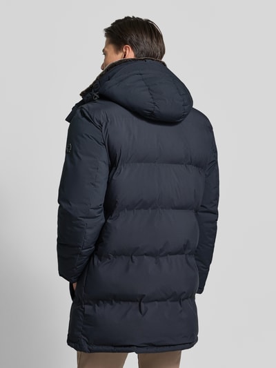 Männermodel trägt Regular Fit Steppmantel mit abnehmbaren Kapuze Modell 'Ambience' von Strellson in Dunkelblau, Herren Steppmantel, Ganzkörperansicht Rückansicht.