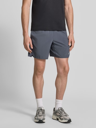 Mężczyznamodel nosi Regular Fit Shorts mit integriertem Slip Modell 'Core' von ASICS TIGER w kolorze szarym, nadruk z logo, elastyczny pas, Szerokość w rozmiarze M: 38 cm, Długość wewnętrzna nogawki w rozmiarze M: 17 cm, Ganzkörperansicht von vorne.