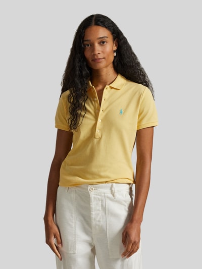 Kobiece modelka nosi Slim Fit Poloshirt aus Baumwoll-Mix von Polo Ralph Lauren, efekt: jednolity kolor, krótki rękaw, kołnierzyk polo, wyhaftowane logo, mieszanka bawełny, pika, widok całej sylwetki z przodu.
