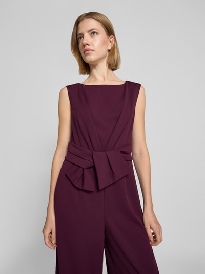 Frauenmodel trägt Regular Fit Jumpsuit in Wickel-Optik von Vera Mont in dunklem Bordeaux, glatte Textur, Nahaufnahme Oberkörper.