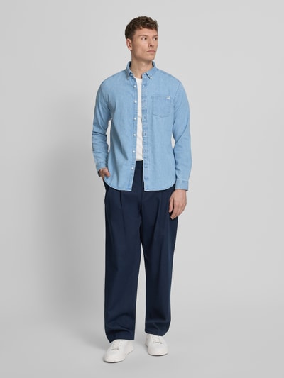 Mannenmodel draagt Regular Fit Jeanshemd mit Button-Down-Kraag van GAP in lichtblauw katoenmix met stretch, borstzak, labeldetail, ruglengte 75 cm, schouderbreedte 46 cm, mouwlengte 66 cm, volledige lichaamsaanzicht van voren.