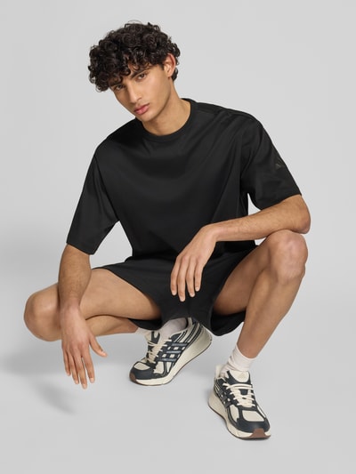Männermodel trägt Relaxed Fit T-Shirt aus reiner Baumwolle von adidas Sportswear, Optik: Unifarben, Ganzkörperansicht von vorne.