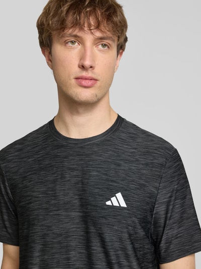 Männermodel trägt T-Shirt mit Label-Print von adidas Training in Schwarz mit Stretch-Anteil und Rundhalsausschnitt, Nahaufnahme Oberkörper.