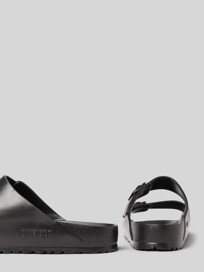 Produktfoto, Slides mit Label-Detail Modell 'ARIZONA EVA' von Birkenstock in Schwarz, strukturierte Sohle, Dornschließe, 4 cm Absatzhöhe, abgerundete Form