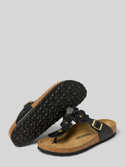 Produktfoto, Zehentrenner aus echtem Leder Modell 'GIZEH FLOWER EMBELLISHMEN' von Birkenstock in Lederoptik, offene Schuhspitze, flache Absatzform, Dornschließe, strukturierte Sohle, Materialverarbeitung aus Glattleder, Farbkombination aus Schwarz und Naturtönen, natürliche Textur.