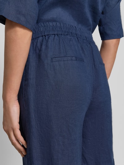 Frauenmodel trägt Leinenhose mit elastischem Bund von Emily Van den Bergh in Dunkelblau, breite Beine, Struktur erkennbar, Detailaufnahme Rückansicht.