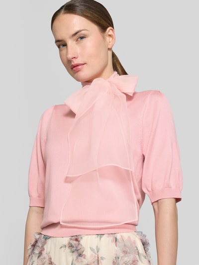 Modelka kobieca ma na sobie Strickshirt mit Schluppe aus Chiffon od Zero w kolorze jasnoróżowym, mieszanka wiskozy, dopasowany krój, kokarda z szyfonu, prążkowane wykończenia, rękaw o dł. 1/2, długość tyłu w rozmiarze 36: 55 cm, długość rękawów: 30 cm, miękka dzianina, tekstura gładka, widoczne delikatne przejścia barw na materiale, całkowite ujęcie tułowia, z przodu, zbliżenie na górną część sylwetki.