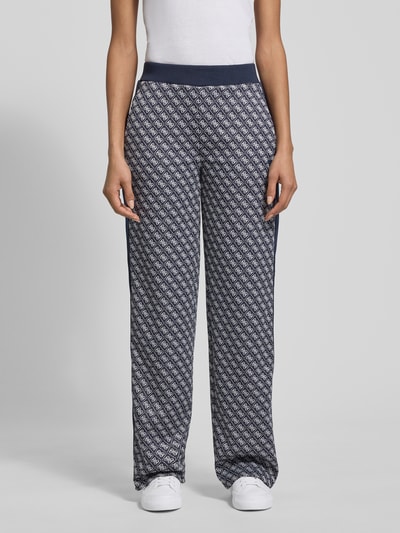 Frauenmodel trägt Wide Leg Sweatpants im Allover-Look Modell 'MAYA' von Guess Activewear mit elastischem Bund, Ganzkörperansicht von vorne.