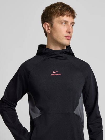 Männermodel trägt Regular Fit Hoodie mit Label-Print von Nike in Schwarz mit grauen Einsätzen, Herren Hoodie von Nike Training, Nahaufnahme Oberkörper.