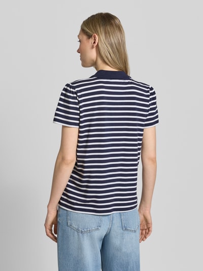 Frauenmodel trägt Regular Fit Poloshirt mit Brusttasche und Motiv-Stitching von More & More im Baumwoll-Modal-Mix mit Stretch-Anteil, Kurzarm, Polokragen, V-Ausschnitt, Rückenlänge bei Größe 36: 60 cm, gestreiftes Muster in Dunkelblau und Weiß, Ganzkörperansicht Rückansicht.