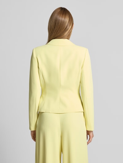Frauenmodel trägt Blazer mit Reverskragen und doppelreihigem Knopfverschluss von Rinascimento, taillierter Schnitt, helle Gelbtöne, Material-Mix mit Stretch-Anteil, Rückenlänge bei Größe S 53 cm, Ganzkörperansicht Rückansicht.