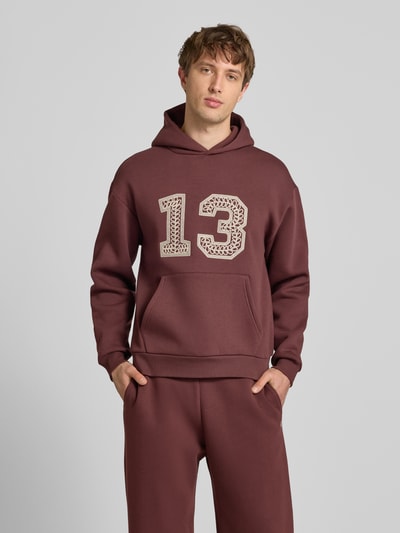 Männermodel trägt Hoodie mit Ketten-Stickerei und Känguru-Tasche von REVIEW aus Baumwoll-Mix in Regular-Fit, Ganzkörperansicht von vorne.