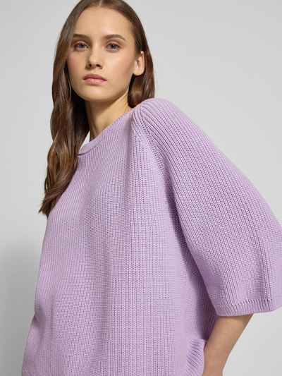 Modelka nosi Oversized Strickpullover aus reiner Baumwolle Modell 'MARGE' od JJXX, lawendowy, okrągły dekolt, rękaw 3/4, dzianinowa faktura, detale prążkowane, widok z przodu zbliżenie na górną część ciała, długość tyłu w rozmiarze S: 59 cm, długość rękawa w rozmiarze S: 23 cm