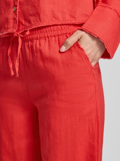 Vrouwenmodel draagt Leinenhose mit elastischem Bund und Tunnelzug van Christian Berg Woman in felrood, zuiver linnen, detailopname heup.