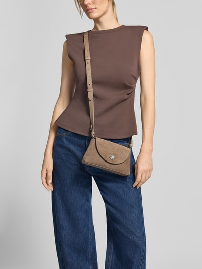 Frauenmodel trägt Shoulder Bag aus echtem Leder Modell 'Nikla' von Coccinelle, braun, strukturierte Oberfläche, Ganzkörperansicht von vorne. Hauptfach mit Überschlag, Schulterriemen, Maße 20x12x5 cm, Riemenlänge 128 cm.