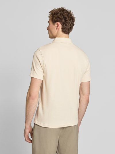 Männermodel trägt Regular Fit Poloshirt aus Baumwoll-Mix Modell 'BLAZE' von SELECTED HOMME in Beige, Piqué-Struktur, Ganzkörperansicht Rückansicht.