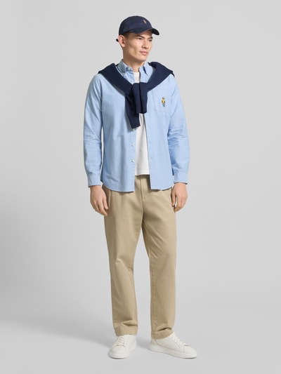 Mannenmodel draagt Custom Fit Freizeithemd met Motiv-Stitching van Polo Ralph Lauren in lichtblauw met borstzak; volledig lichaamsaanzicht van voren. Gemaakt van puur katoen met button-down kraag, knoopsluiting en Motiv-Stitching, ruglengte maat M 78 cm, schouderbreedte 43 cm, mouwlengte 62 cm.