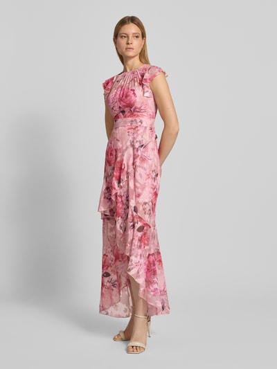 Frauenmodel trägt Regular Fit Abendkleid mit Rüschenbesatz von Lipsy aus Mesh mit floraler Allover-Print, taillierter Passform, kurzärmelig, Raffungen, in Rosa- und Pinktönen auf fließendem Stoff, Details zu Rückenlänge 128 cm, Brustweite 40 cm, Ganzkörperansicht von vorne.