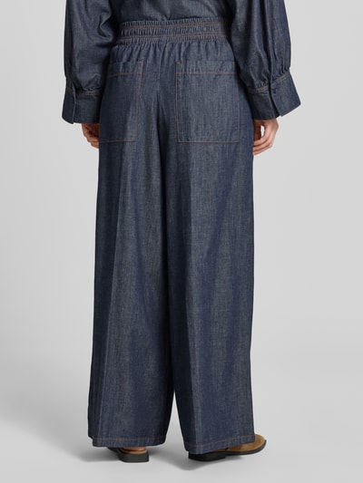 Frauenmodel trägt Wide Leg Jeans mit elastischem Bund Modell 'CEILING' von Drykorn aus Reine Baumwolle, dunkelblau, breite Form, sichtbare Nähte, Damen Jeans, Ganzkörperansicht Rückansicht, Bundweite bei Größe 27/34: 35 cm, Innenbeinlänge: 78 cm.