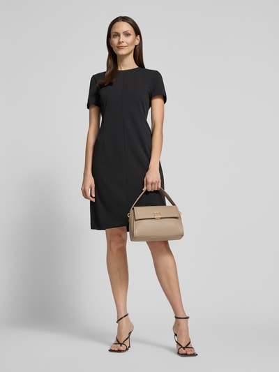 Vrouwenmodel draagt Handtasche mit Label-Applikation van CK Calvin Klein in beige met klep, hengsel en schouderriem, volledig frontaal.