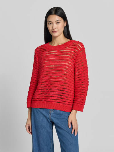 Vrouwenmodel draagt Oversized Pullover in semitransparant design Model 'Ajour' van monari, puur katoen, oversized fit, tricotlook, ruglengte maat 36: 54 cm, mouwlengte maat 36: 49 cm, rood met gehaakte textuur. Ganzelichaamsaanzicht van voren.