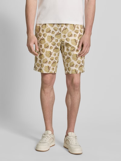 Mężczyznamodel nosi Bermudas mit Kordelzug und Eingrifftaschen od bugatti, len z bawełną, krój straight fit, motyw roślinny w beżowo-zielonych odcieniach, szerokość w rozmiarze 50: 42 cm, długość nogawki 26 cm, widok całej sylwetki z przodu.