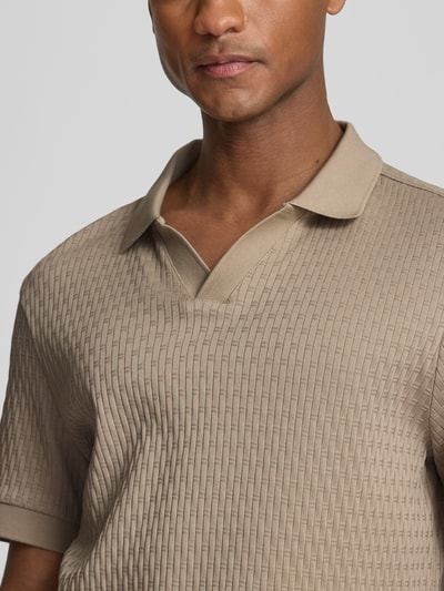 Männermodel trägt Regular Fit Poloshirt mit V-Ausschnitt Modell 'Rauljose' von JOOP! Collection aus reiner Baumwolle mit Strukturmuster, Nahaufnahme Oberkörper.