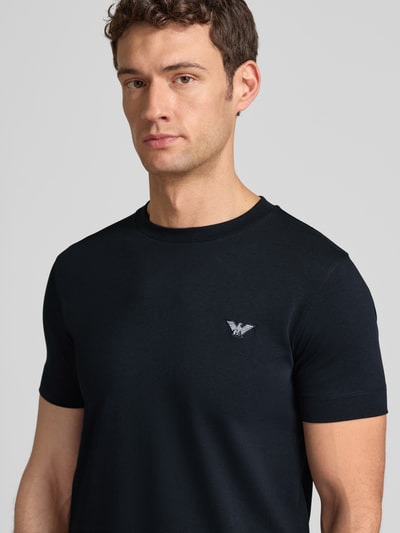 Männermodel trägt T-Shirt mit Label-Stitching und Rundhalsausschnitt von Emporio Armani, reine Baumwolle, Slim Fit, Nahaufnahme Oberkörper.
