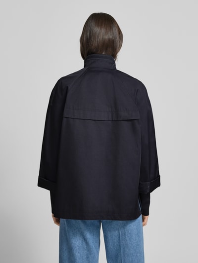 Modelka prezentuje Relaxed Fit Jacke mit Stehkragen od comma, mieszanka bawełny, krój relaxed fit, stójka, wpuszczane kieszenie, elastyczne zakończenia rękawów, pełna listwa guzikowa, długość tyłu w rozmiarze S 70 cm, szerokość ramion w rozmiarze S 48 cm, szerokość klatki piersiowej w rozmiarze S 58 cm, długość rękawów w rozmiarze S 73 cm, kolor ciemnogranatowy, widoczna struktura tkaniny, całkowity widok z tyłu.