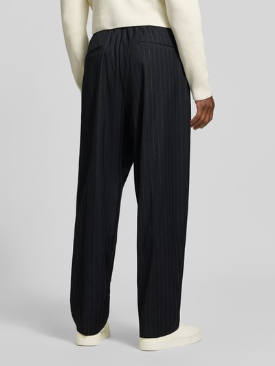 Männermodel trägt Stoffhose mit Bügelfalte Modell 'LEON' von Antony Morato, Wide Fit, Material-Mix, Ganzkörperansicht Rückansicht.