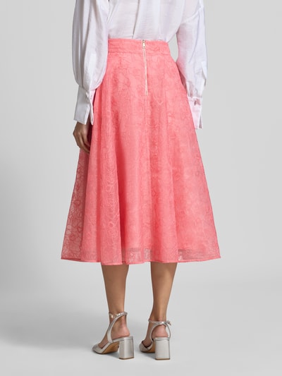 Männermodel trägt spódnica midi z haftem na całej powierzchni Model 'Krizie' od Ted Baker, Linia a, halka pod spódnicę, szerokość w rozmiarze 36: 38 cm, całkowita długość w rozmiarze 36: 80 cm, widok całej sylwetki od tyłu.