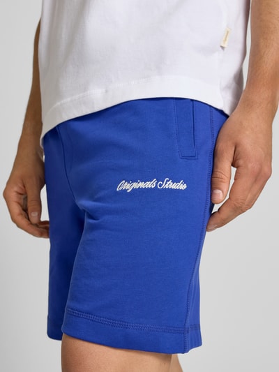 Mannenmodel draagt Sweatshorts met Stitching model 'KARL' van Jack & Jones, regular fit, katoenmix, elastische tailleband, blauwe kleur, detailopname rechterbeen.